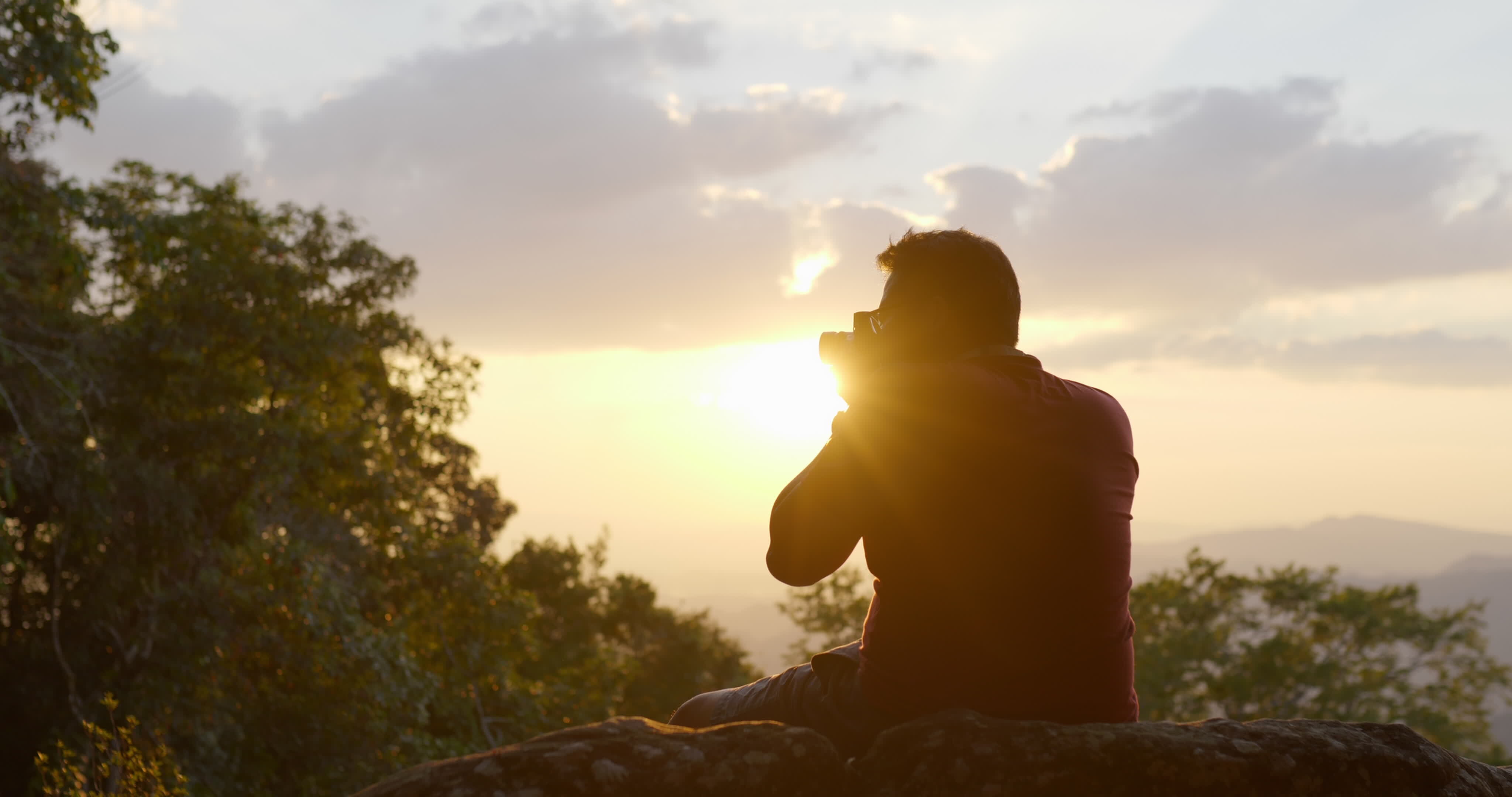 Slow motion in backlit shot, Young backpacker man sitting on rocky