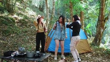 grupo belas mulheres asiáticas amigos viajantes relaxando na frente da barraca de acampamento, eles gostam de cantar uma música dançando e bebendo cerveja com diversão e feliz juntos