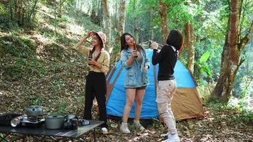 grupp vackra asiatiska kvinnor vänner resenärer kopplar av framför campingtältet, de njuter av att sjunga en sång med dans och dricka öl med roligt och lyckligt tillsammans video