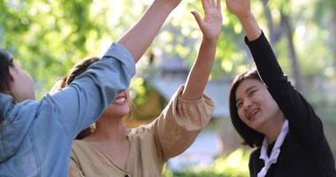 Handheld shot, Group of women giving five to each other on camping with toothy smile and happy together at front of camping tent in forest video