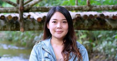 Handheld shot, Close up face of Young pretty woman standing looking to camera with smile on camping site in forest video