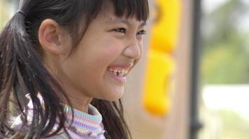 Handheld shot, Headshot portrait Asian lovely girl stand looking forward talking and laughing with fun at playground