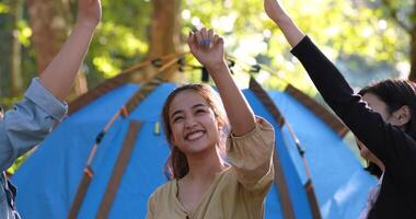 Handaufnahme, Gruppe von Frauen, die sich beim Camping mit einem Lächeln und einem glücklichen Zusammensein vor dem Campingzelt im Wald fünf geben video