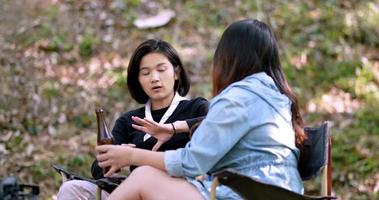 groep mooie aziatische vrouwen vrienden reizigers ontspannen aan de voorkant van de campingtent, ze genieten van praten en bier drinken met plezier en gelukkig samen video