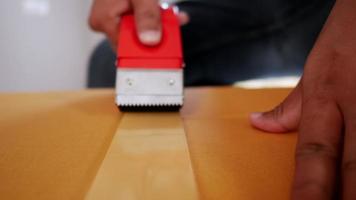 Zeitlupenaufnahme, Vorderansicht Hand des Mannes verwendet Klebeband, um Karton zu schließen, große Kiste zum Bewegen zu versiegeln, neues Hauskonzept, selektiver Fokus video