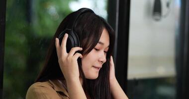 Close up shot, Pretty Asian teenage sitting and enjoy to listening musice from wireless headphone and singing together. People and lifestyle concept. video