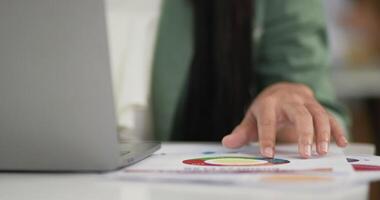 cerrar la mano de una mujer de negocios leyendo gráficos financieros información comercial con una computadora portátil. concepto de negocio. video