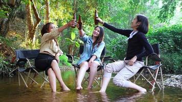 une jeune femme asiatique cuisine et son amie aime utiliser un smartphone prendre une photo le repas dans la casserole, ils parlent et rient avec plaisir ensemble en camping dans un parc naturel video