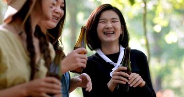 groep mooie aziatische vrouwen vrienden reizigers ontspannen aan de voorkant van de campingtent, ze staan te dansen en bier te drinken en praten met plezier en gelukkig samen