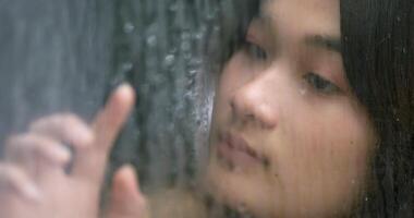 Close up shot,  Asian sad young woman looking through window on rainy day. Depression concept. video