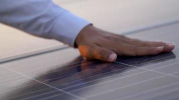 Close up hand of engineering or Technician man checking on operation of sun and cleanliness of photovoltaic solar panels at sunset