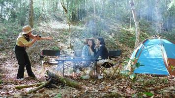 uit de hand geschoten, jonge mooie foto maken met de camera twee vriendinnen zittend op de campingtent in het bos op vakantie, jonge Aziatische groepsvrouw reizen buiten kamperen. video