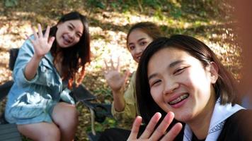 foto de mão, grupo de mulheres jovens sentadas em frente à barraca de acampamento, elas gostam de fazer videochamadas juntas enquanto acampam no parque natural