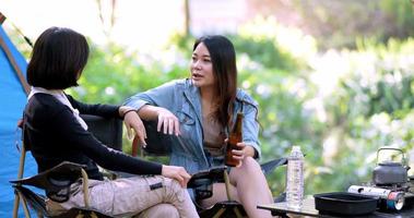 groep mooie aziatische vrouwen vrienden reizigers ontspannen aan de voorkant van de campingtent, ze genieten van praten en bier drinken met plezier en gelukkig samen video