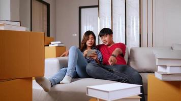 tir au ralenti, jeune couple assis sur un canapé-lit et liste de contrôle tout en comptant les boîtes après le déménagement dans leur nouvelle maison, nouveau concept de maison video