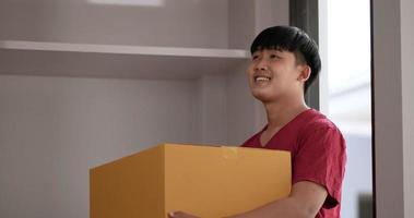 Zeitlupenaufnahme, asiatisches junges Paar mit Pappkarton geht glücklich in neues Haus, neues Hauskonzept