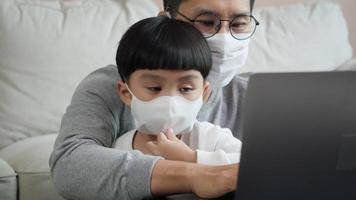 Father and son with laptop and mask