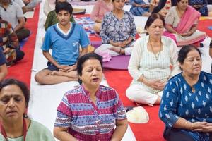New Delhi, India, June 19 2022 -Group Yoga exercise session for people of different age groups in Balaji Temple, Vivek Vihar, International Yoga Day, Big group of adults attending yoga class in temple photo