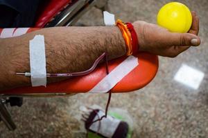 donante de sangre en el campamento de donación de sangre sostenido con una pelota hinchable en la mano en el templo balaji, vivek vihar, delhi, india, imagen para el día mundial del donante de sangre el 14 de junio de cada año, campamento de donación de sangre foto