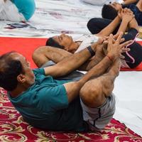 New Delhi, India, June 19 2022 -Group Yoga exercise session for people of different age groups in Balaji Temple, Vivek Vihar, International Yoga Day, Big group of adults attending yoga class in temple photo