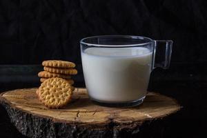 leche fresca y saludable y pila de galletas sobre fondo negro foto