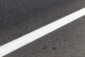 close up of an asphalt road with white road markings photo