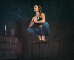 charming girl in a sports uniform does yoga in an old room with a fireplace and candles photo