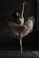 a charming ballerina in a bodysuit poses ballet elements in a headdress in a photo studio