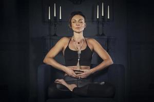 charming girl in a sports uniform does yoga in an old room with a fireplace and candles photo
