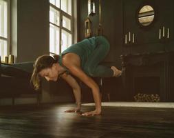 charming girl in a sports uniform does yoga in an old room with a fireplace and candles photo