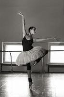 una bailarina encantadora en un traje de cuerpo posa elementos de ballet en un tocado en un estudio fotográfico foto