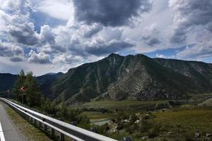 cinta de la carretera entre las laderas de las montañas en las extensiones de altai en un día de verano foto