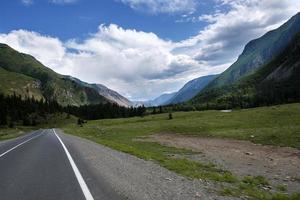 cinta de la carretera entre las laderas de las montañas en las extensiones de altai en un día de verano foto