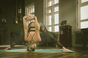 una chica encantadora con uniforme deportivo hace yoga en una habitación antigua con chimenea y velas foto
