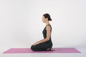 una chica encantadora demuestra estiramientos y asanas de yoga en un estudio fotográfico foto