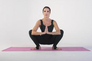 una chica encantadora demuestra estiramientos y asanas de yoga en un estudio fotográfico foto