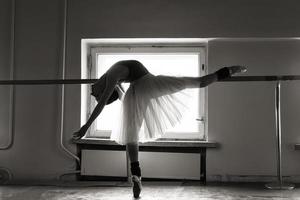 a charming ballerina in a bodysuit poses ballet elements in a headdress in a photo studio