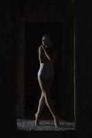 a charming ballerina in a bodysuit poses ballet elements in a headdress in a photo studio