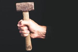 sledge-hammer tool in a man hand on black background - maintenance sercice concept photo