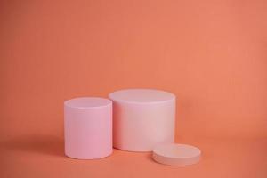 podio vacío para mostrar productos cosméticos. arreglo de plataforma en color rosa pastel en estilo minimalista moderno. composición de diseño de cilindros y cubos para fondo femenino foto