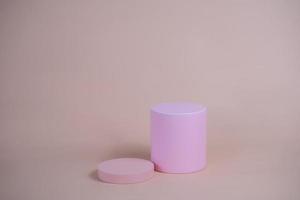 podio vacío para mostrar productos cosméticos. arreglo de plataforma en color rosa pastel en estilo minimalista moderno. composición de diseño de cilindros y cubos para fondo femenino foto