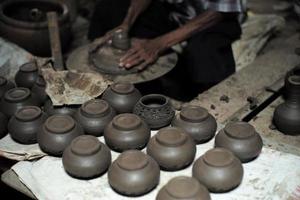 Top view group of clay jars in the production process with defocused old worker molding the clay work in background photo