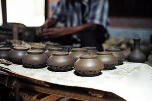 Group of clay jars in the production process with defocused old worker molding the clay work in background photo