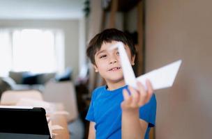 Selective focos on Happy school boy eyes looking at origami Swan paper. Kid learning paper art origami lesson, Child having fun doing Art and Craft at home, Home schooling concept photo