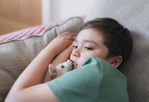 retrato dramático niño aburrido cara mirando profundamente en el pensamiento, niño solitario con cara pensante sentado solo en el sofá, niño preescolar molesto con cara infeliz o triste, niños malcriados, salud mental foto