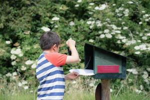 niño usando sello de tinta en papel blanco, niño parado en la estación de rastro de sello de tinta, explorador infantil y aprendiendo sobre la naturaleza salvaje, niño divirtiéndose con actividades al aire libre o aventuras en el bosque con viaje escolar foto