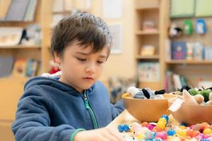 Kid playing colourful wooden blocks  and soft toy in play room,Young boy playing alone in school library,Educational toys for preschool and kindergarten child. Creative concept photo