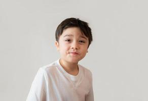 Portrait  cute happy young boy wearing white T- shirt looking up with surprised face, Head shot Positive kid with smiling face and making funny face. Children days concept photo