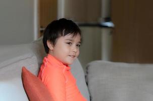 Portrait kid in swiming suit, Happy young boy sitting on sofa looking out with smiling face. Child relaxing in living room get ready to go to swim. Healthy children concept photo