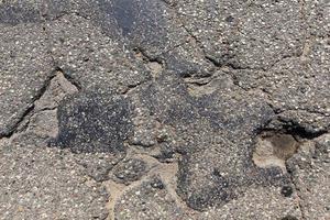 an asphalt road with a lot of holes and damage photo